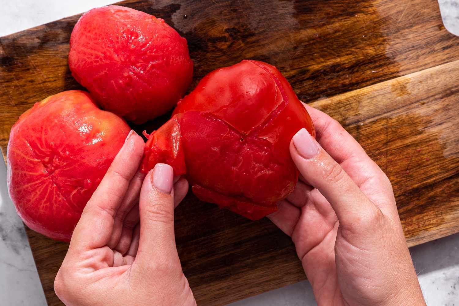 Tomato skins peeled off of blanched tomatoes on a cutting board for bruschetta recipe