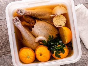 Brined whole turkey in a bucket with brining liquid.