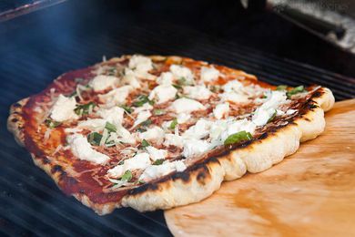 Using a wooden peel to remove a pizza from the grill