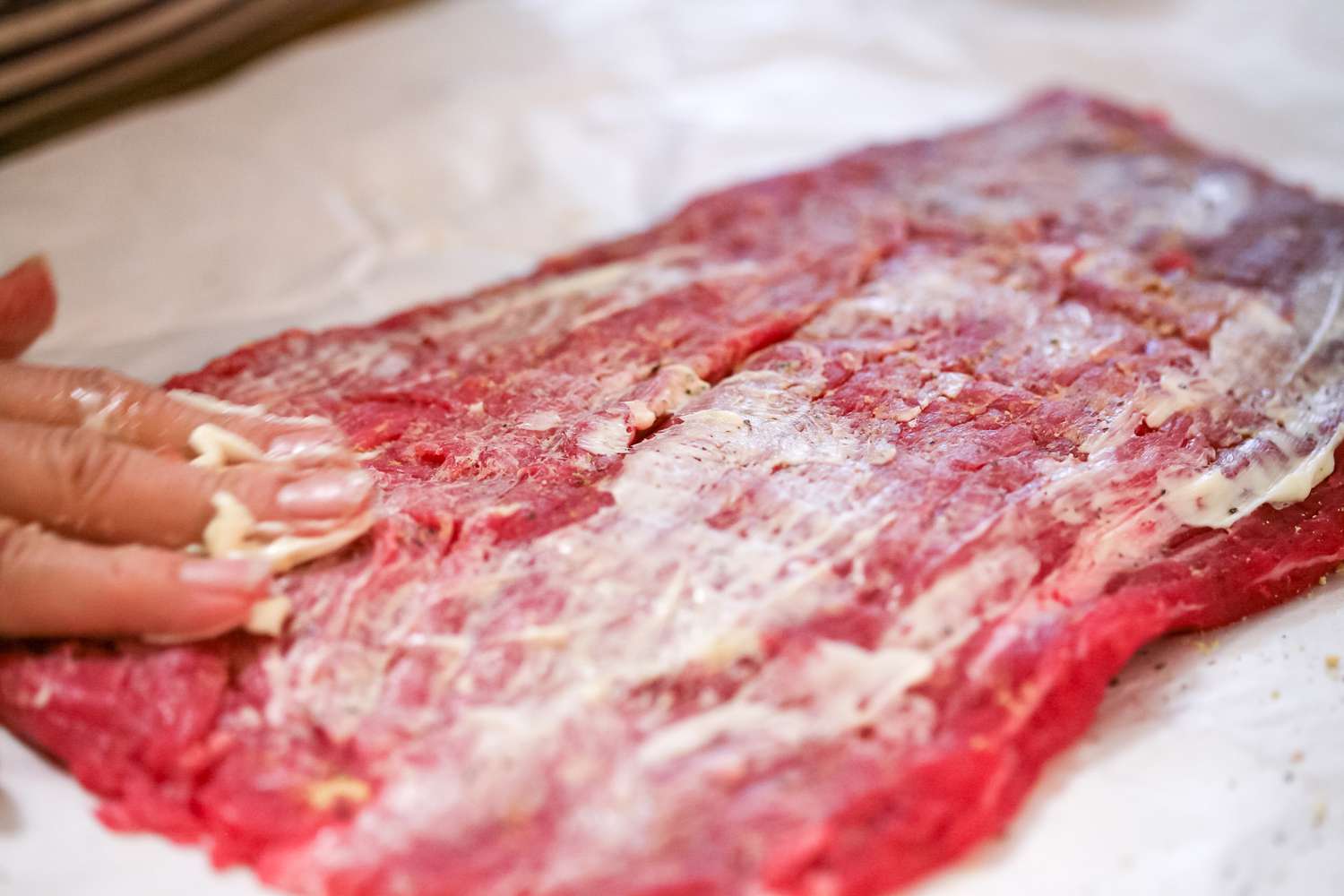 Rubbing flank steak with butter to show how to cook flank steak.