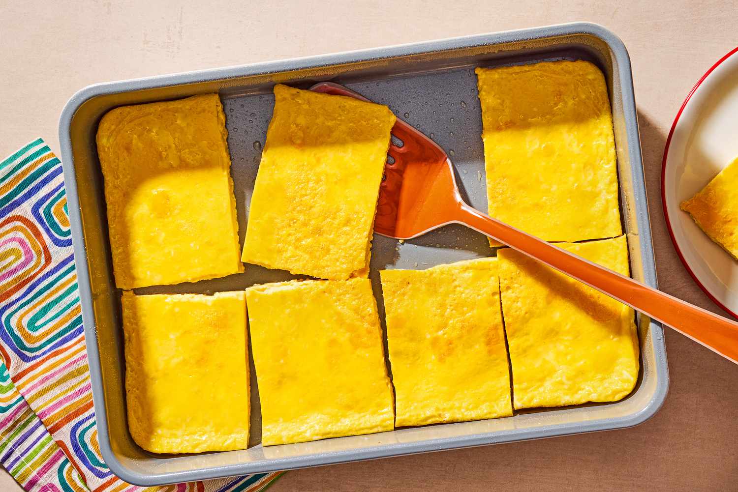 Overhead shot of baked egg cut into eight pieces, in a rectangular baking dish