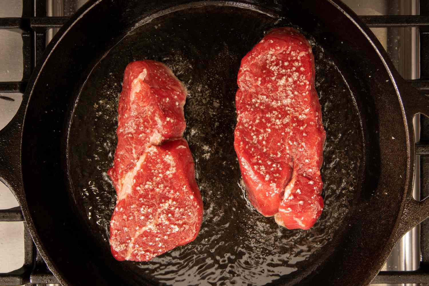 Filet mignon steaks searing in a skillet on the stove