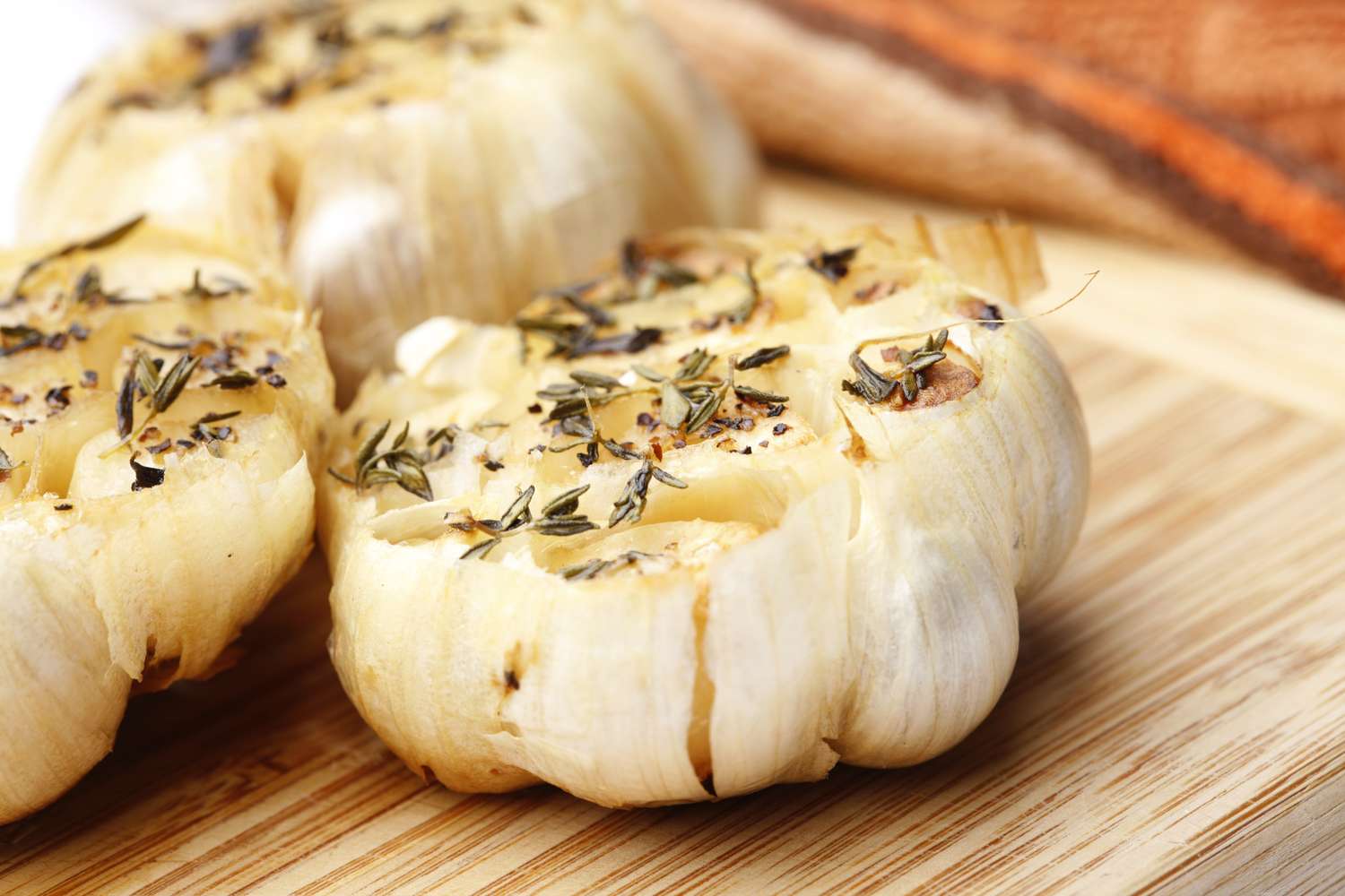 Roasted garlic seasoned with herbs on a wooden surface
