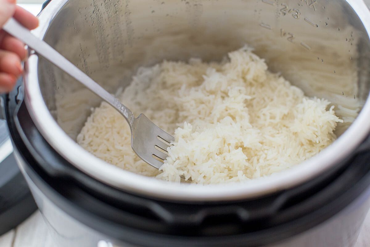 Rice being fluffed in an Instant Pot with a fork