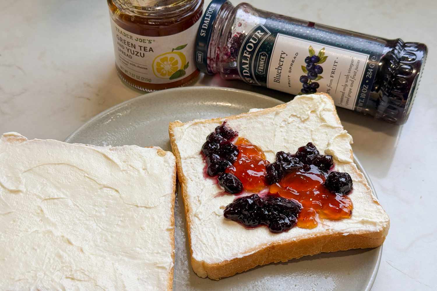 Side shot of Korean Breakfast Toast on a plate and in the background, two jars of jam