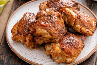A plate with four crispy skinned and seasoned cooked chicken thighs