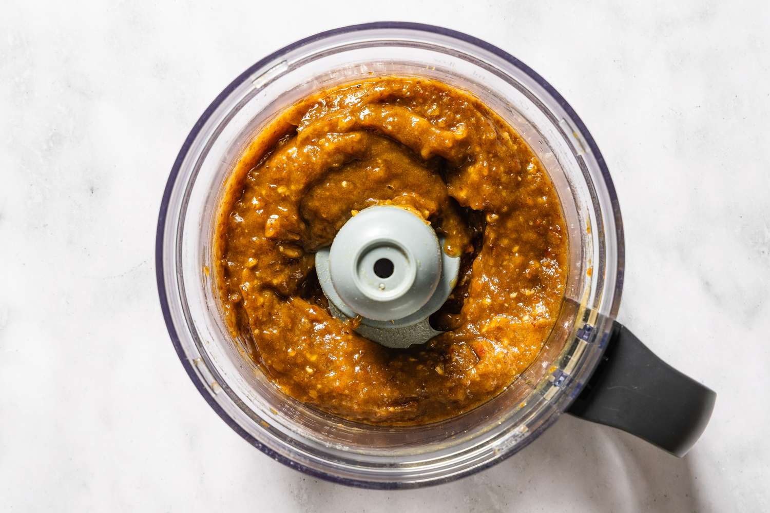 A food processor containing a blended mixture of sticky toffee pudding ingredients