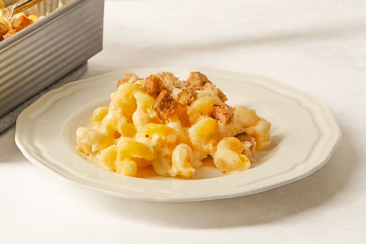 Cooked macaroni and cheese served on a white plate topped with breadcrumb crust
