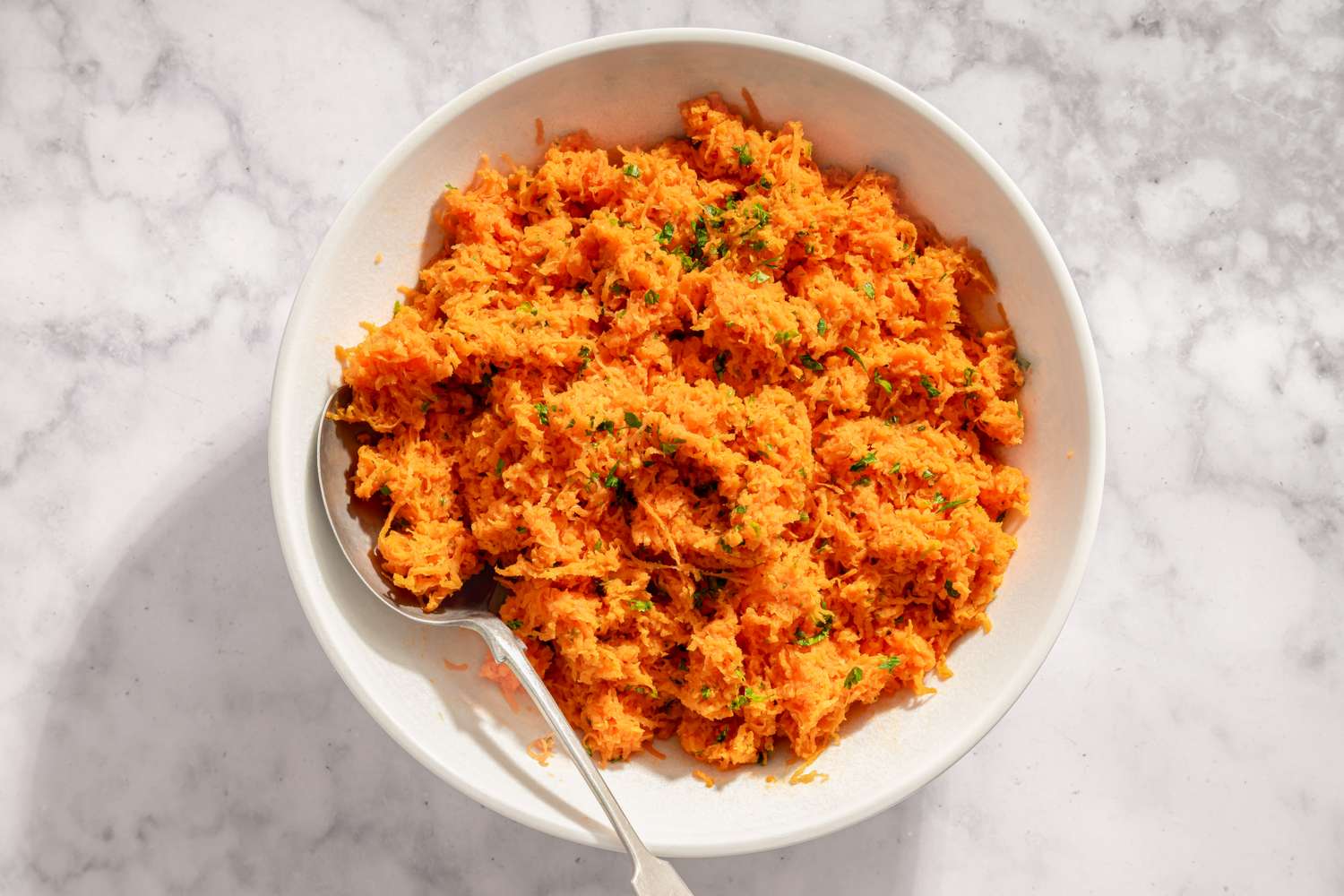 French carrot salad in a bowl with a serving spoon