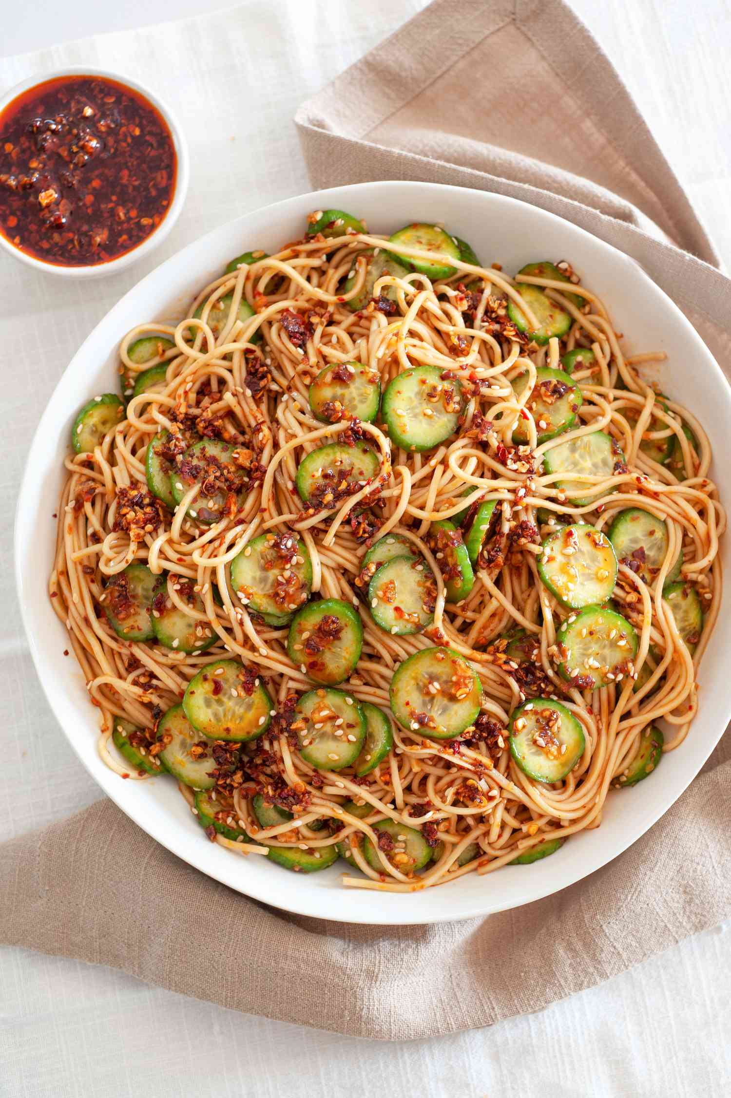 Large bowl of spicy noodles with cucumbers and chili crisp.