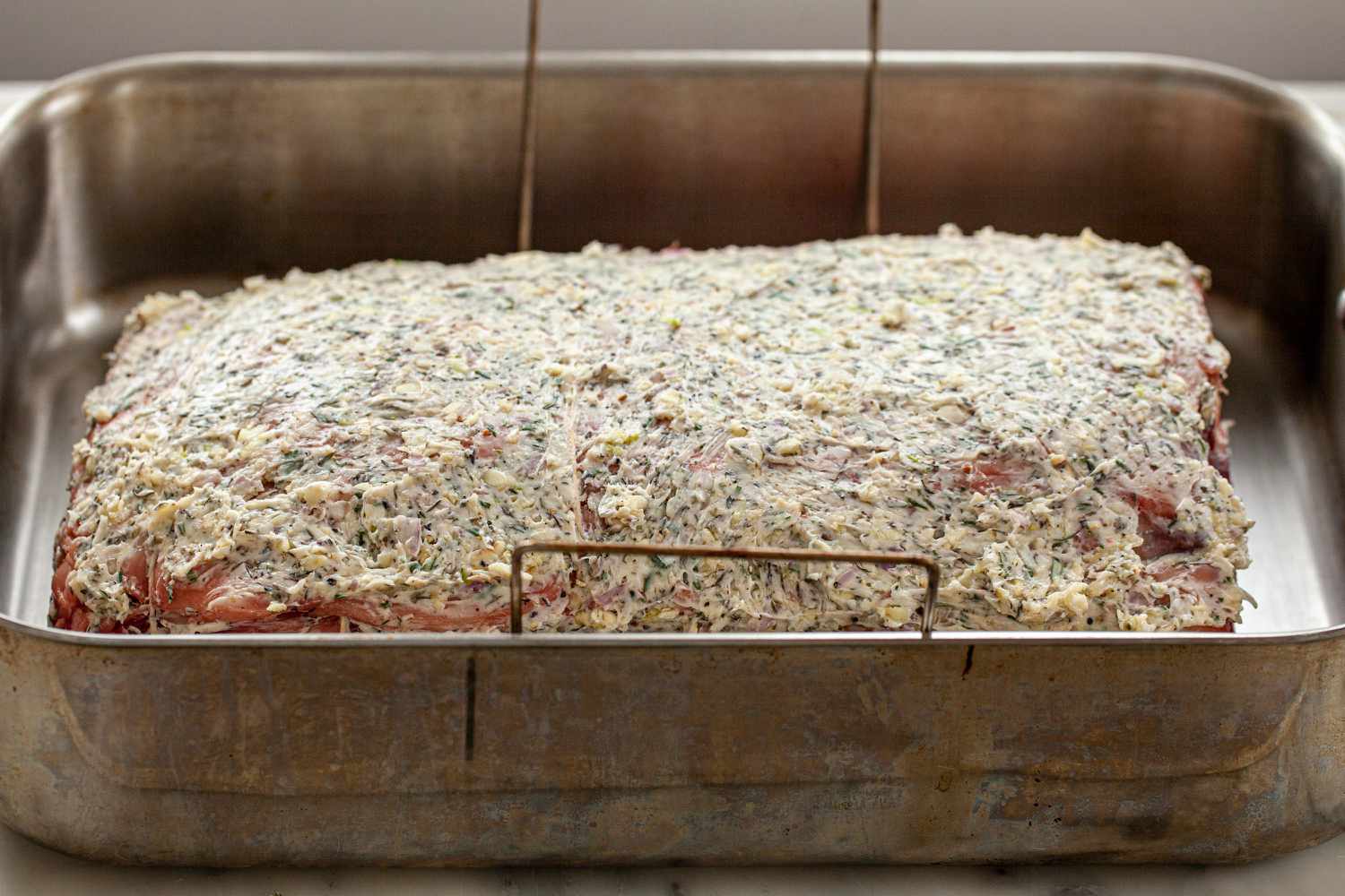 Prime Rib with Thyme, Rosemary, Shallot Herb Butter in a roasting pan and ready to be cooked.