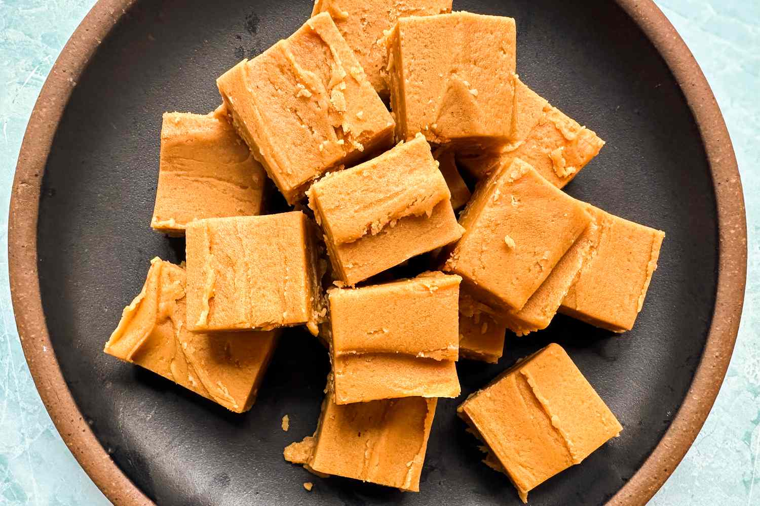 Over head shot of peanut butter fudge squares on a black and brown ceramic plate for 2-ingredient peanut butter fudge recipe