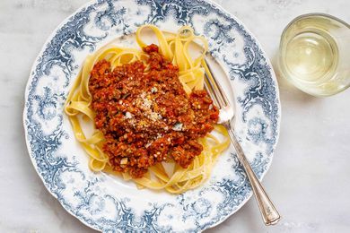 A beautiful fast bolognese sauce on a blue patterned plate with noodles and fork.