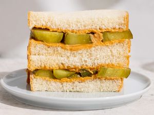 Peanut butter and pickle sandwich stacked on a white plate