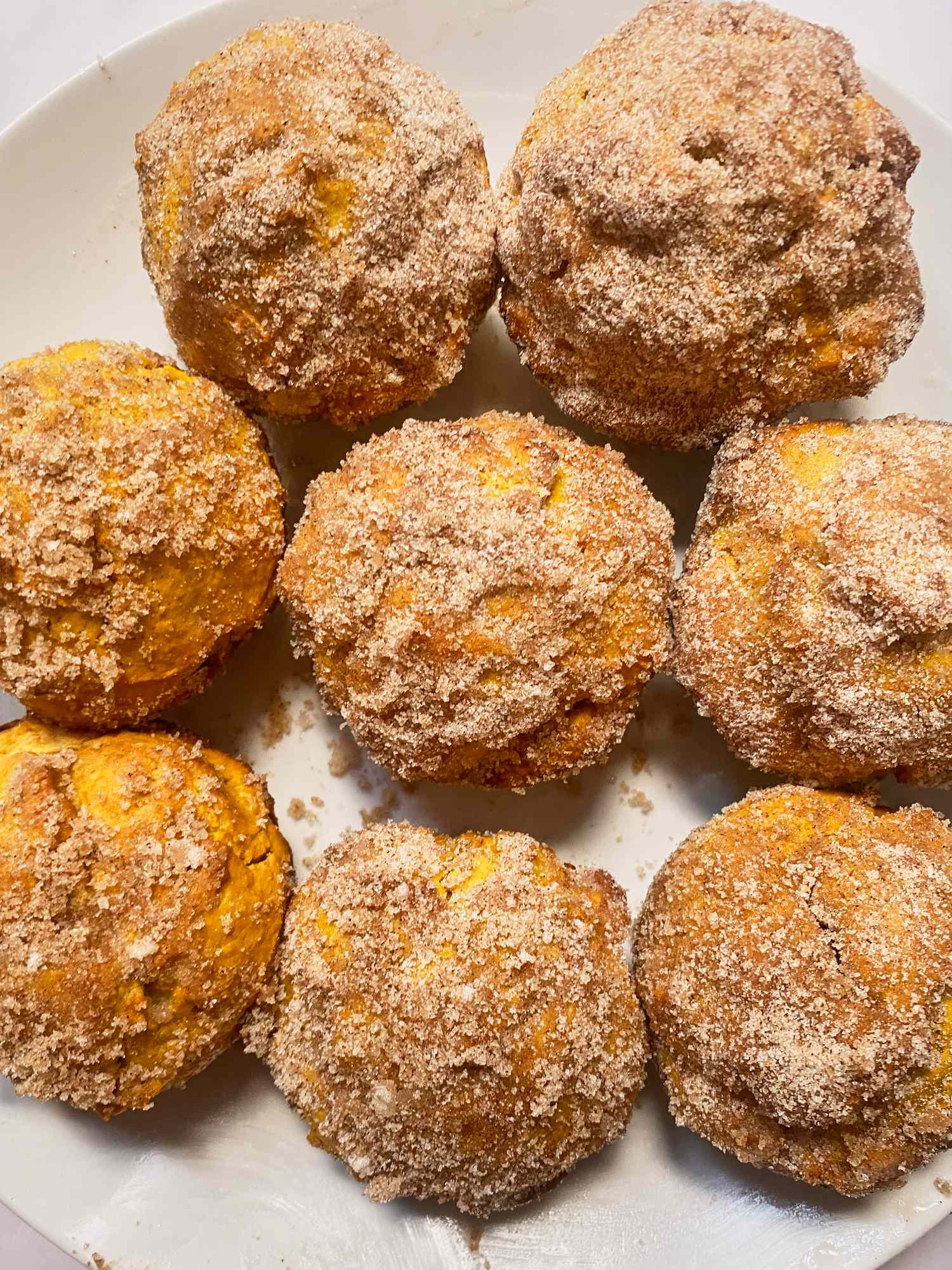 A plate of multiple pumpkin donut muffins topped with sugar and spice