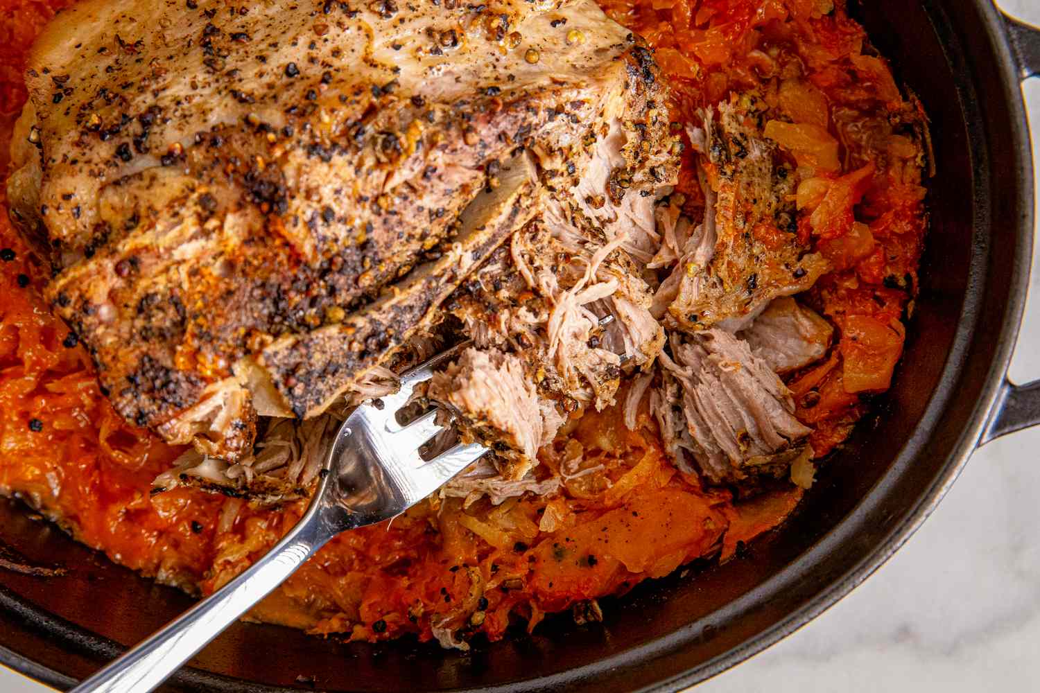 Braised pork roast with sauerkraut in a pot partially shredded to reveal the texture