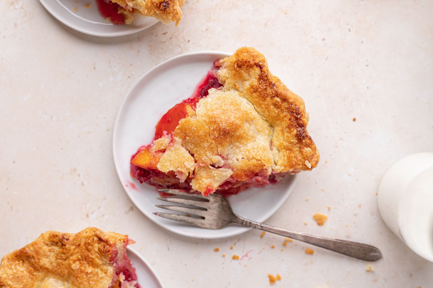 Overhead view of a slice of stone fruit and berry pie.