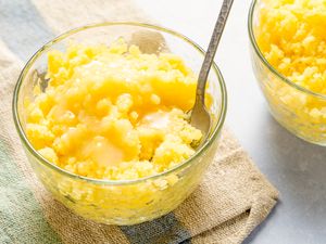 Glass bowls of pineapple coconut granita with spoons, set on a textured cloth
