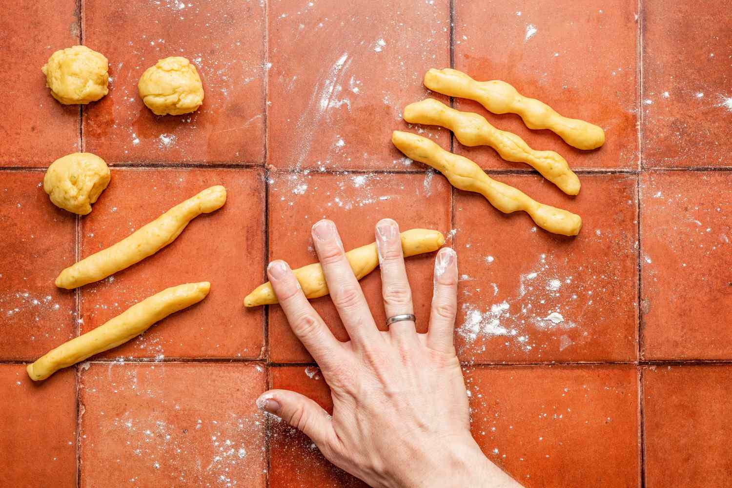 Hand rolling out a piece of dough into a "bone" and pressing down to create bone-like indents