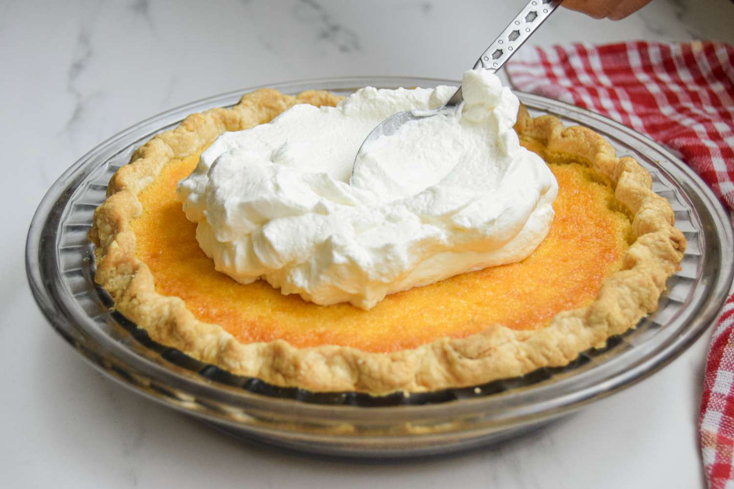 Adding whipped cream to a buttermilk pie for a buttermilk pie recipe.