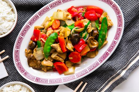 Platter of Chop Suey at a Table Setting With Chopsticks on Napkins and Bowls of Rice, All on a Grey Kitchen Towel