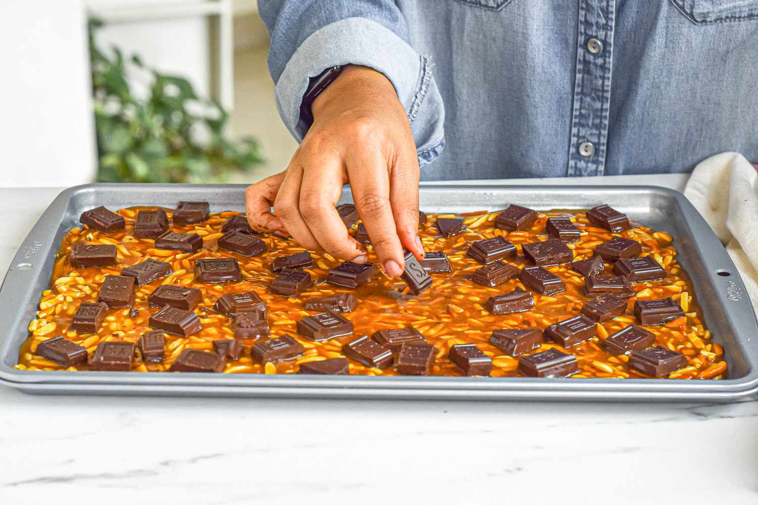 Adding chocolate to the top of the almond roca candy.
