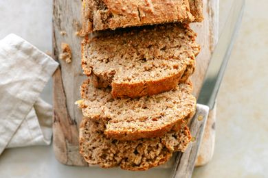 Sliced banana bread on a wooden board with a knife placed beside it
