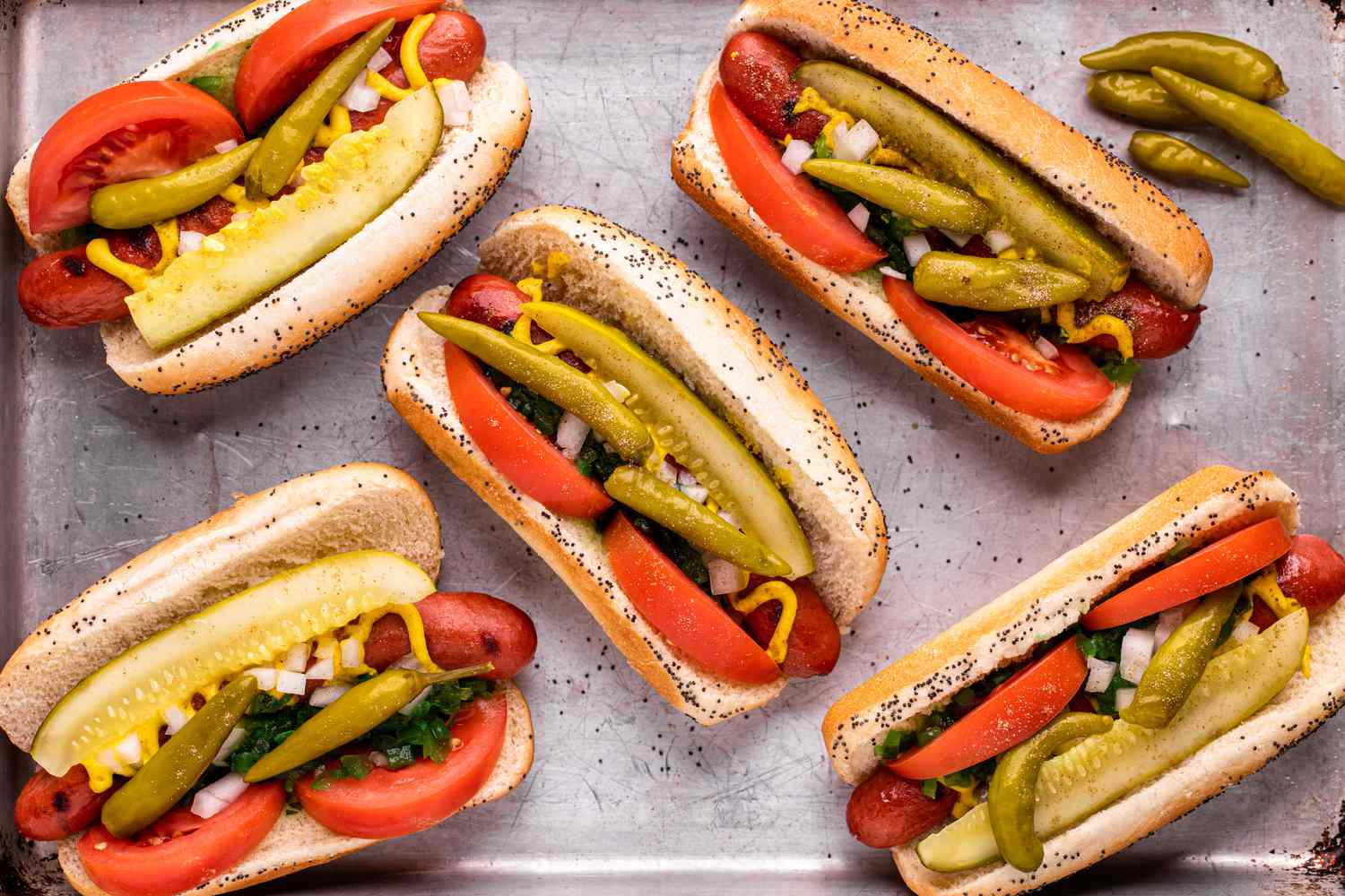 Overhead view of a sheet pan with Chicago-style hot dogs on it.