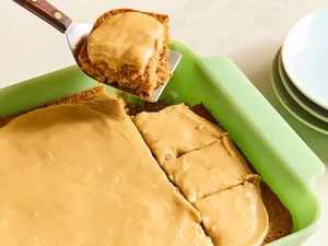 baking dish with Grandma’s Oatmeal Cake, slices cut and one slice on a metal spatula with plates for serving