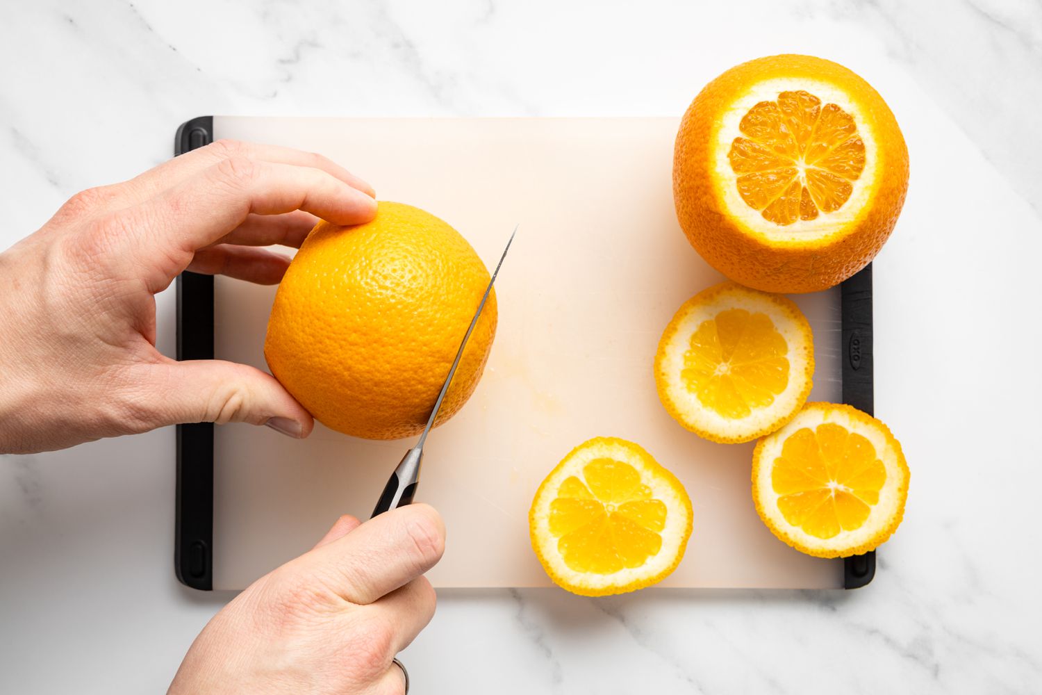 Tops and Bottoms of an Orange Cut Off on a Cutting Board Next to an Already Cut Orange for Chocolate Covered Orange Peels Recipe