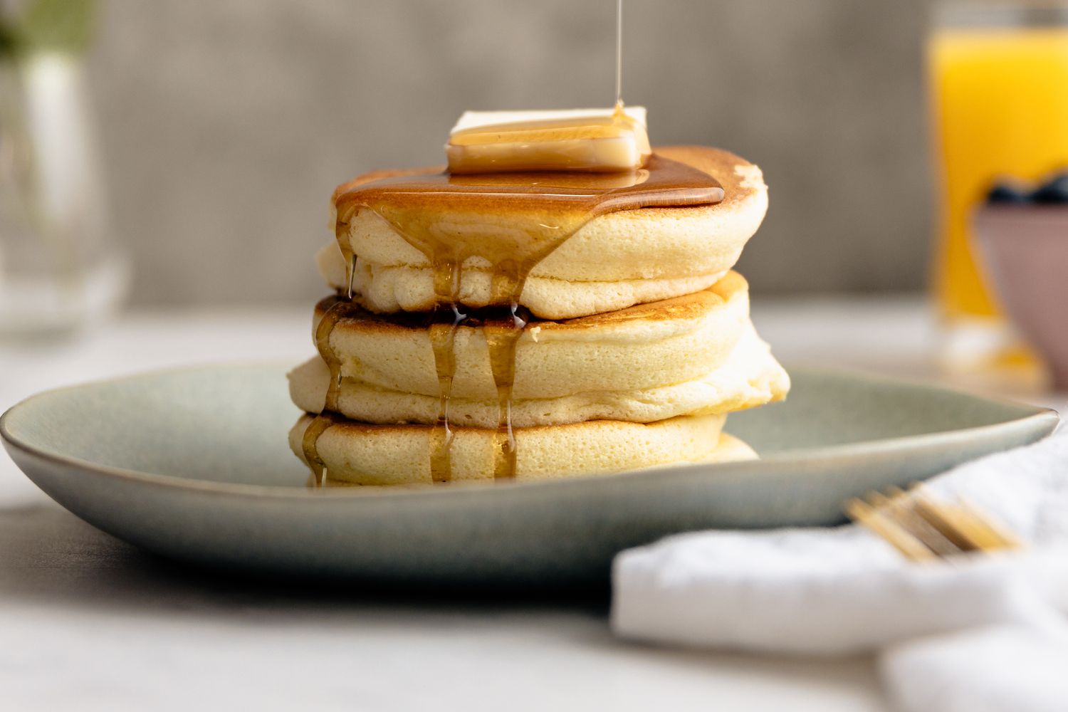 Stack of Japanese Souffle Pancakes on a Plate Topped with Butter and Maple Syrup