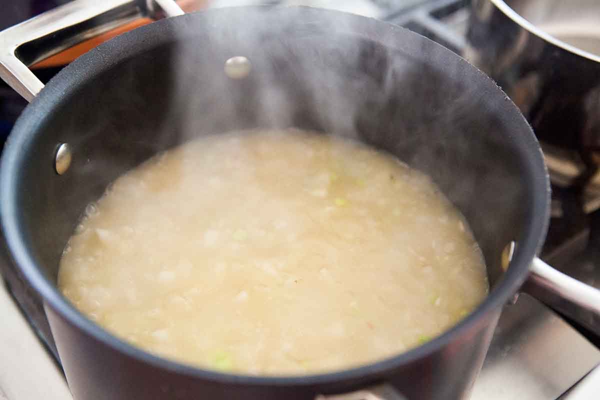 Brown rice and stock simmering in a sauce pan