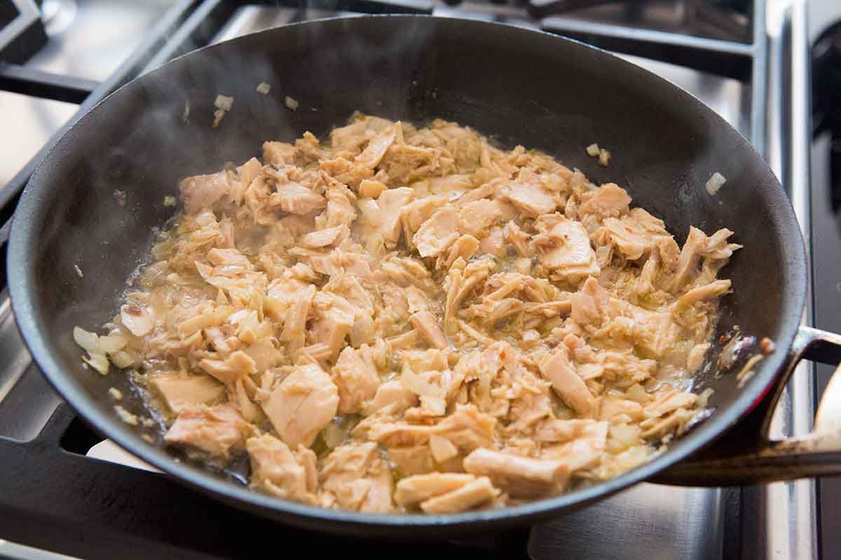 canned tuna cooking for tuna pasta with tomatoes and olives