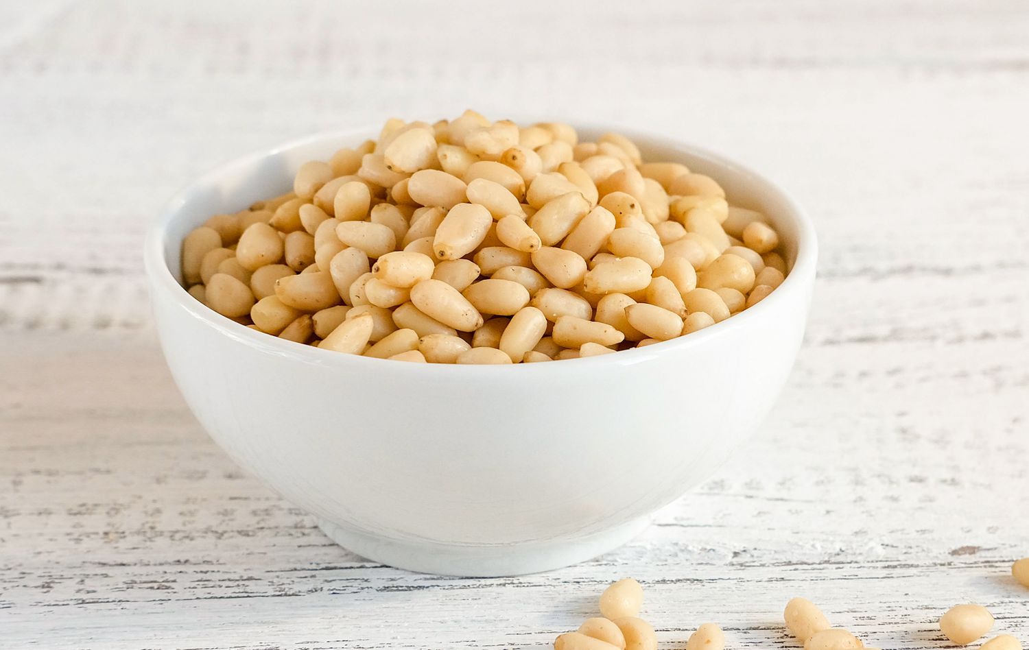 A white bowl of pine nuts