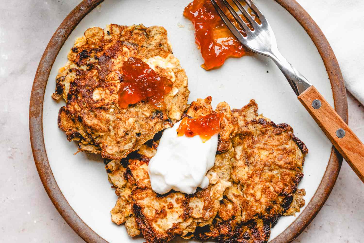 Overhead view of a plate of Matzo Brei Pancakes with a fork gray countertop