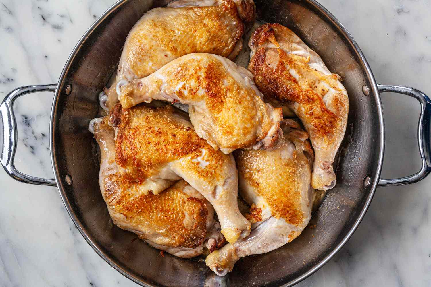 Browned chicken legs added to a pot for coco van.