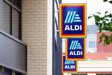 Three Aldi store signs on the exterior of a building visible in an urban setting with brick and glass details
