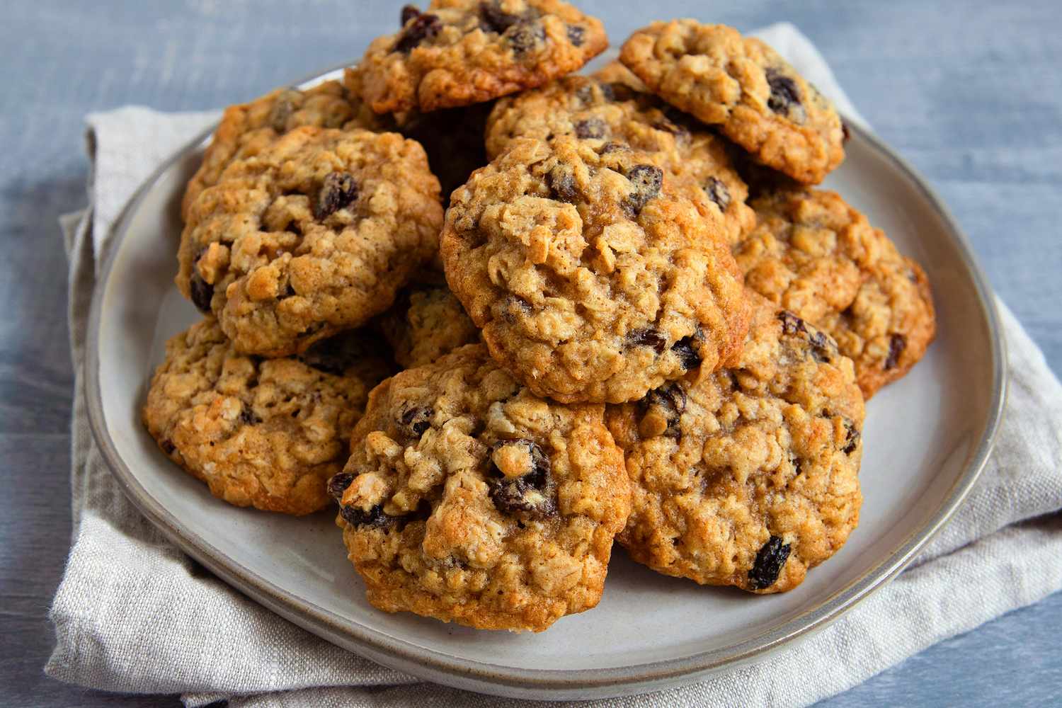 A plate of oatmeal raisin cookies on a linen cloth