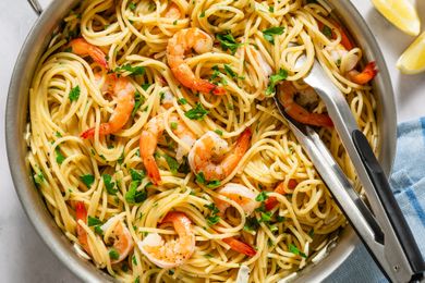 Pasta with shrimp and herbs served in a skillet with tongs on the side