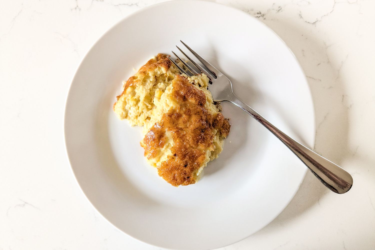one serving of Nigella Lawson's Sweet Corn Pudding on a small plate with a fork