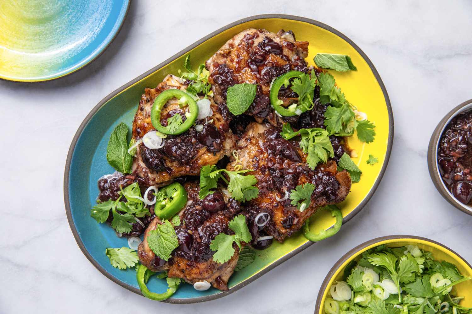 Platter of sticky chicken garnished with herbs and onions
