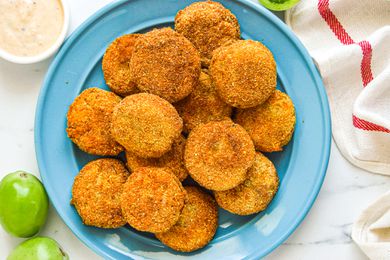 Overhead view of a plate of green tomatoes that have been breaded and fried.