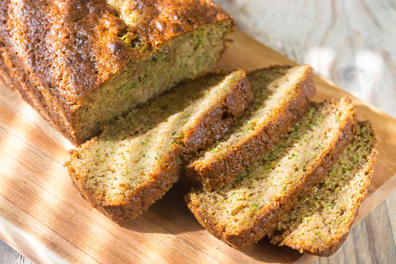 zucchini bread sliced and loaf on a wooden cutting board 