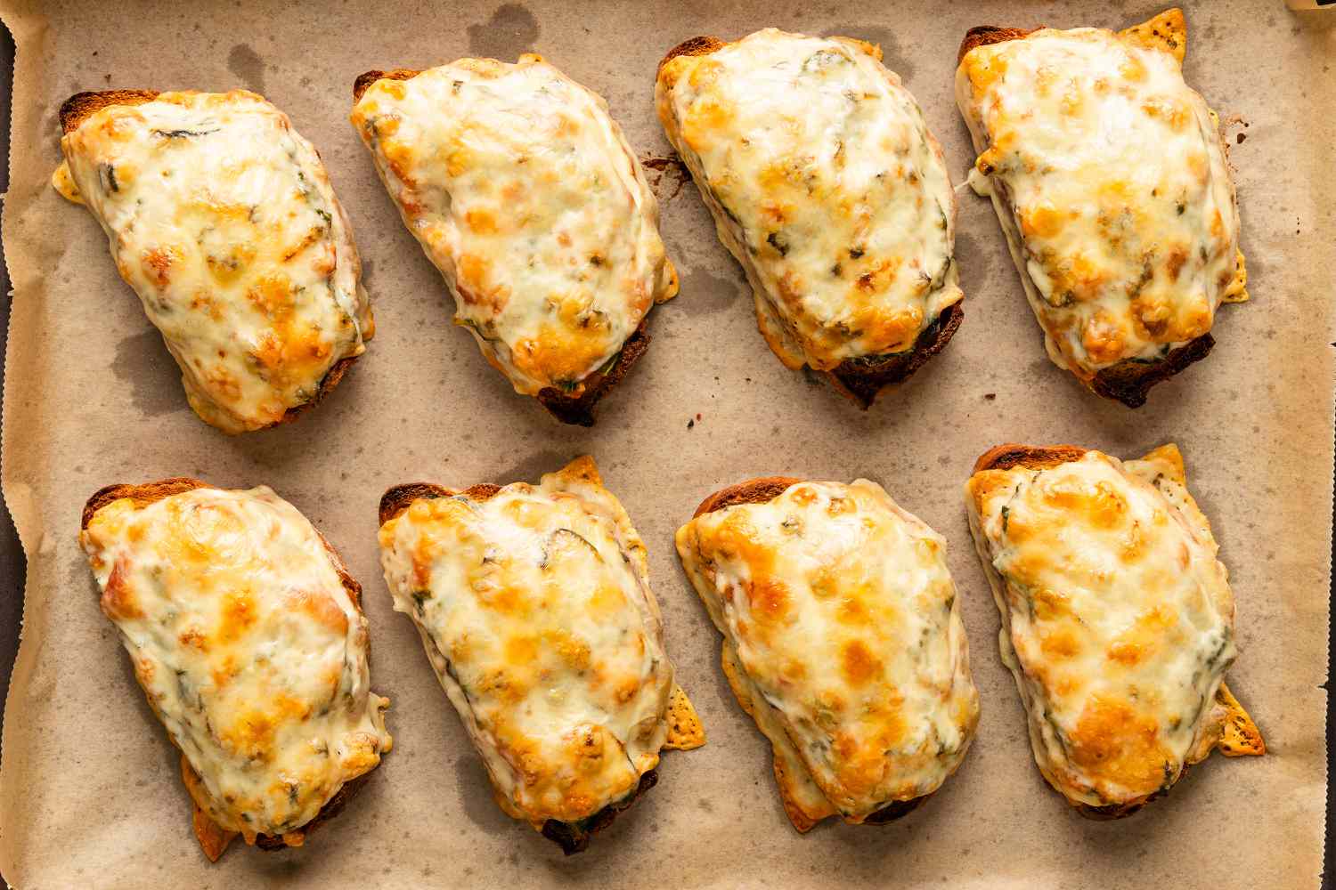 overhead view of cheesy Soupy Toasts on a parchment lined sheet-pan