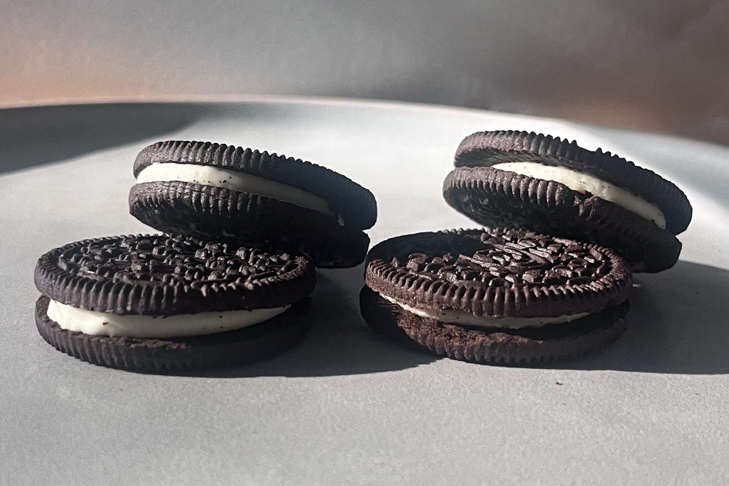 Four sandwich cookies with cream filling shown on a surface