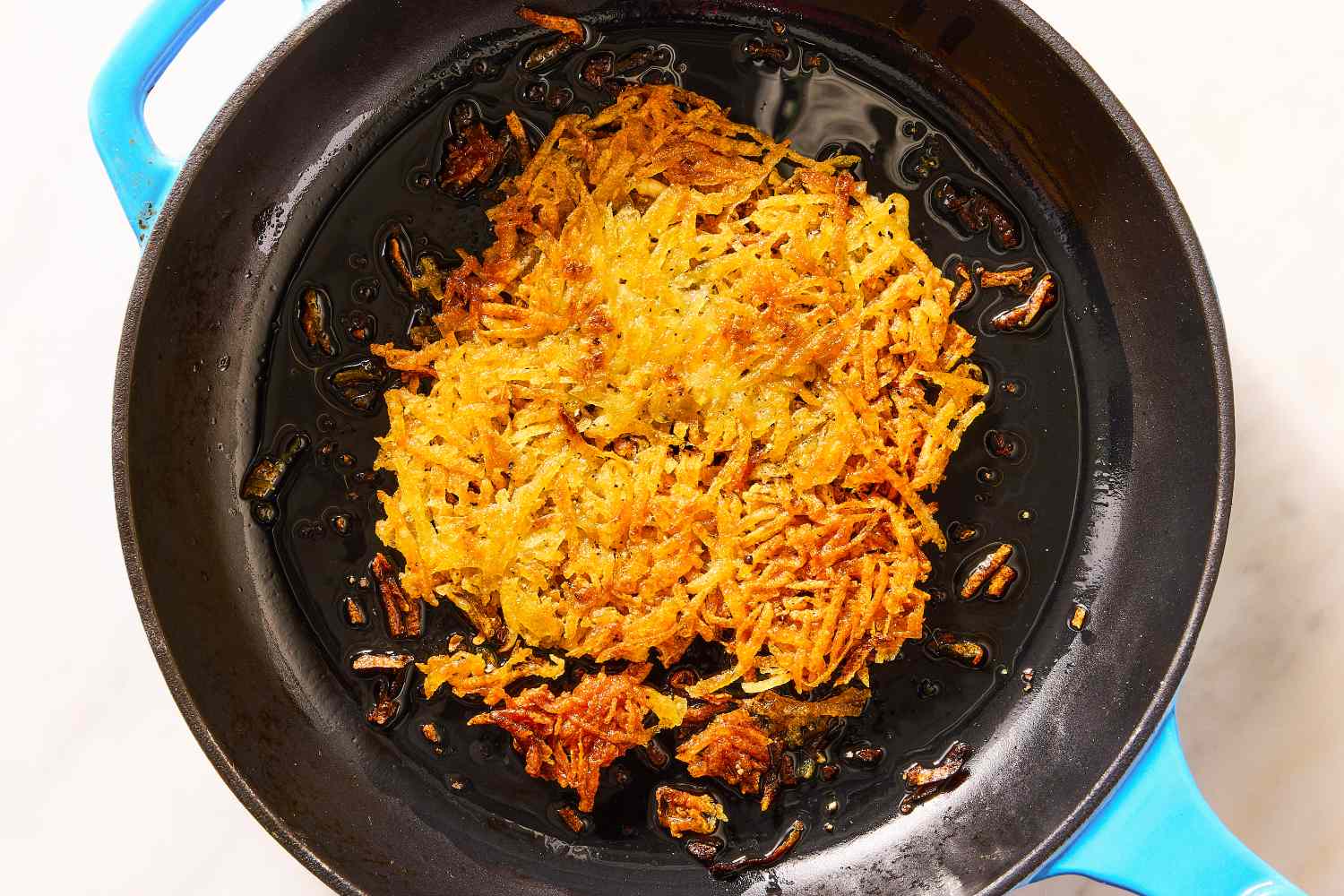Crispy hash browns cooking in a cast iron skillet