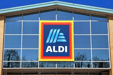 Exterior of an Aldi supermarket with a prominent sign displaying the store's logo near the entrance