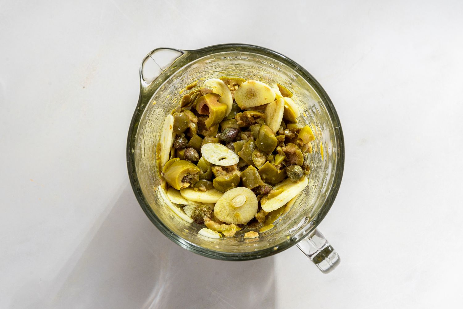 garlic, capers, and olives in a measuring cup for caponata pasta recipe