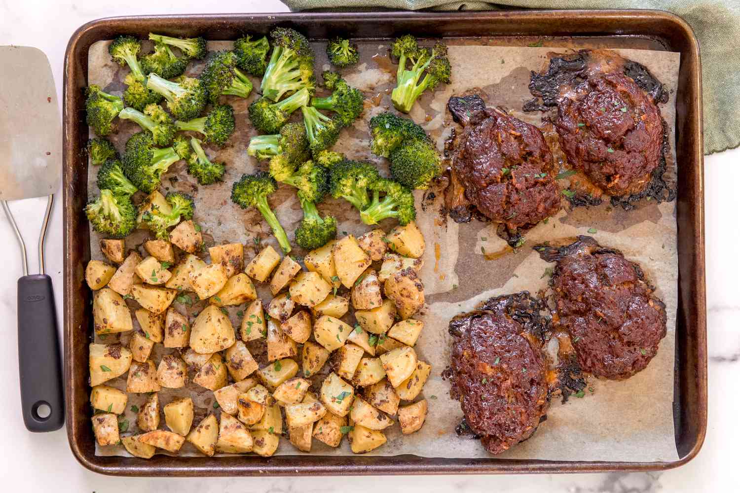 Mini meatloaves with broccoli and potatoes on a sheet pan.