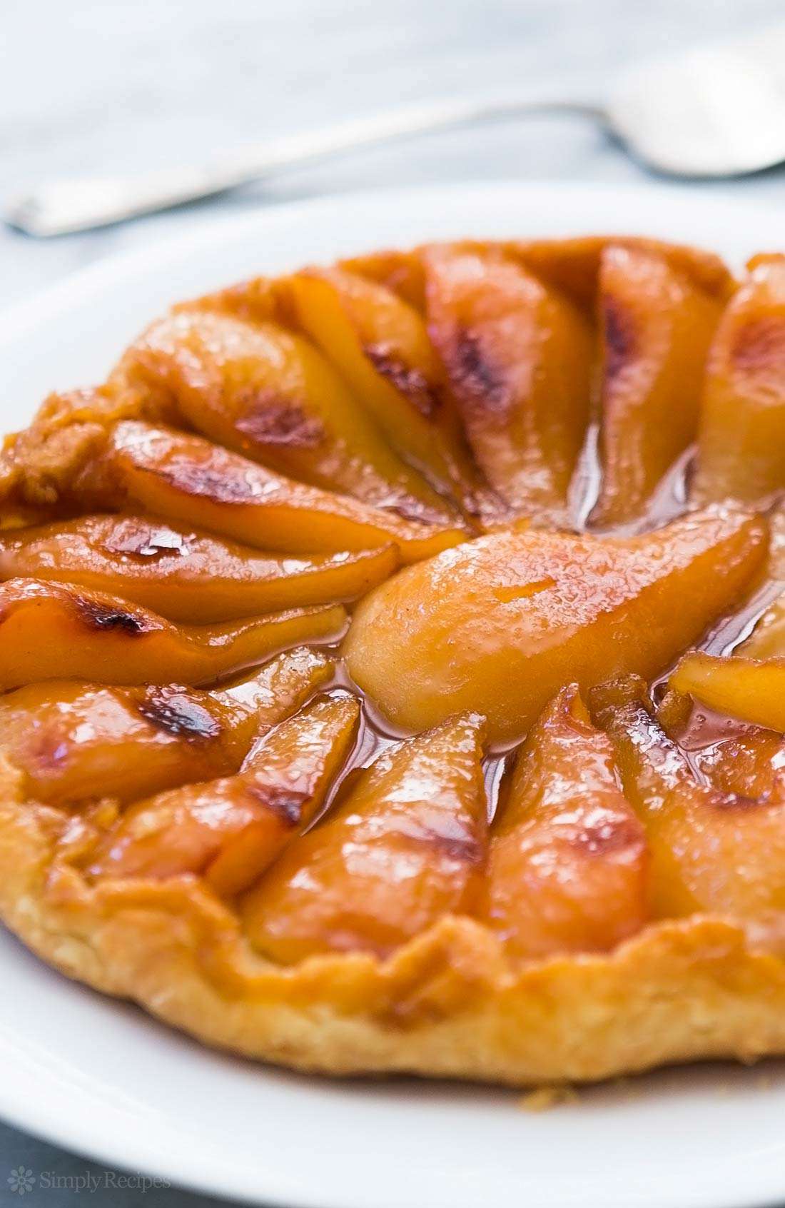 A close up side shot of pear tarte tatin ready to slice and serve